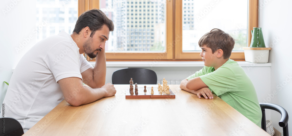 Clever boy plays chess with his father Clever boy plays chess with his father