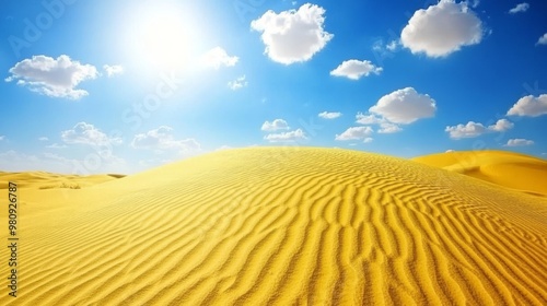 Beautiful sand dunes under a bright sun with scattered clouds in a clear blue sky on a sunny day.