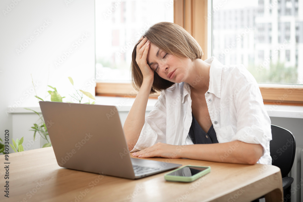 Young attractive woman sitting at the table and working on laptop in the kitchen at home Young attractive woman sitting at the table and working on laptop in the kitchen at home
