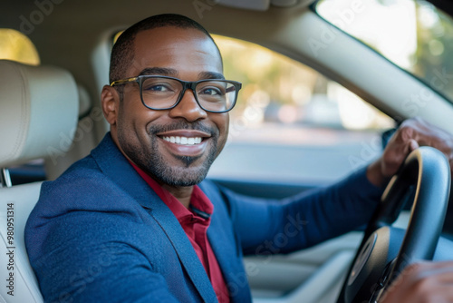 Smiling man in a suit driving a car during the day in a city