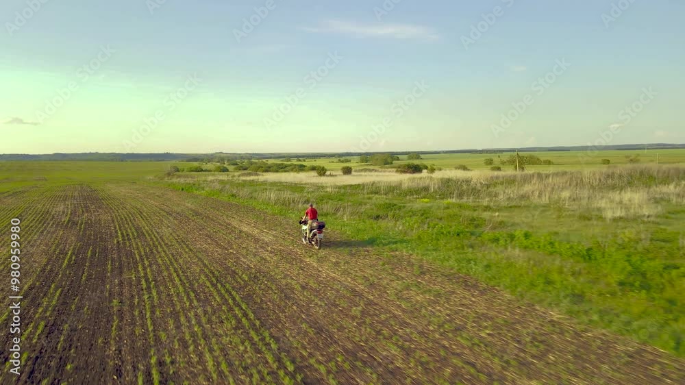 A guy rides a motorcycle through an agricultural field. 4k footage A guy rides a motorcycle through an agricultural field. 4k footage