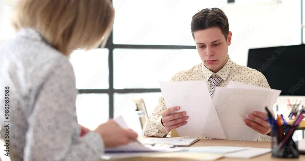 Serious business partners colleagues are sitting at table. Discussing documents and managers are reading sales report Serious business partners colleagues are sitting at table. Discussing documents and managers are reading sales report