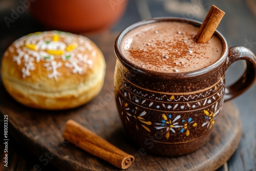 Mexican cup with steaming hot chocolate and cinnamon stick and pan de muerto bun on wooden board, dark wooden table. Concept Day of the Dead, traditional Mexican drink