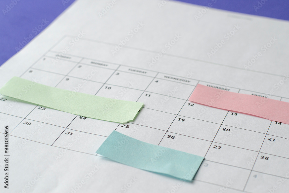 Calendar of the month and several colored adhesive notes to highlight the activities to be done. Copy space. Concept of time organization and achievement of objectives.