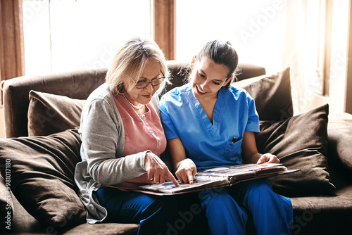Senior, woman and caregiver with photo album on sofa for memories, nostalgia and remember with support. Elderly, person or female nurse in assisted living with talking of pictures, empathy or bonding