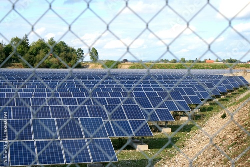 Solarpark mit Sonnenkollektoren mitten in der Natur. Ein Maschendrahtzaun im Vordergrund (unscharf). Klimaneutrale Stromerzeugung im Allgäu, Bayern.  photo