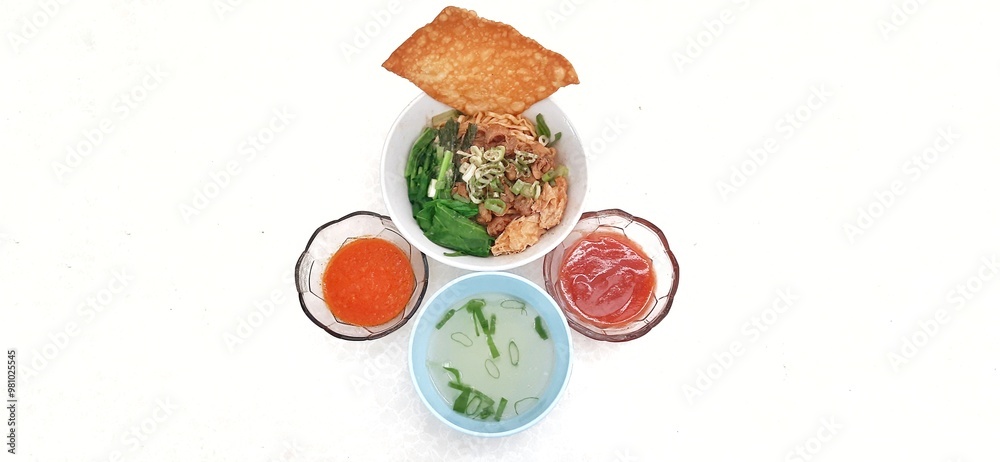 Chicken noodle or mie ayam with fukien, fried dumplings and vegetables served on bowl isolated on white background. Popular street food in Indonesia Chicken noodle or mie ayam with fukien, fried dumplings and vegetables served on bowl isolated on white background. Popular street food in Indonesia
