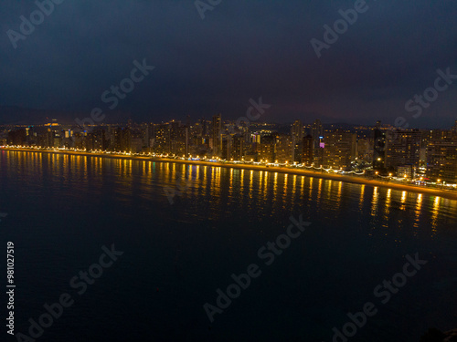 Night time aerial photo of the town of Benidorm in Spain and the beach known as Playa Levante beach showing hotels, buildings, restaurants and the coastline front.