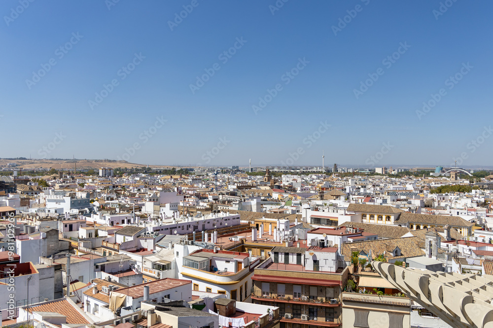 Panoramic view of Seville showcasing the city's rooftops, historic buildings, and modern structures under a clear blue sky. Panoramic view of Seville showcasing the city's rooftops, historic buildings, and modern structures under a clear blue sky.