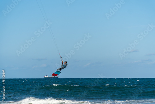 A young man kitesurfing at sunset in the sea.