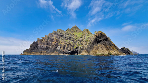 A breathtaking wide shot of Skellig Michael, showcasing its towering cliffs, ancient monastic ruins, and the vibrant interplay of ocean waves against the rugged landscape.