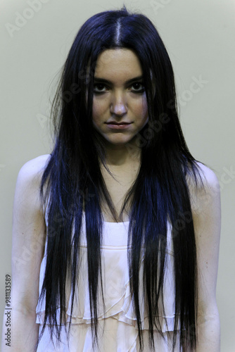 Woman with long black hair and a white dress stares directly at the camera with an intense expression, Milan, Italy photo