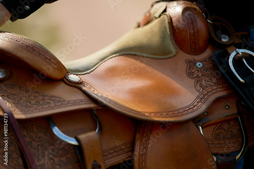 Close-up of a detailed leather horse saddle with tooling and silver conchos. photo