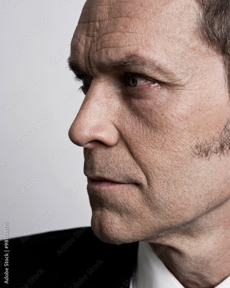 Close-up of a mature man in a suit looking to the side with a focused expression. Close-up of a mature man in a suit looking to the side with a focused expression.