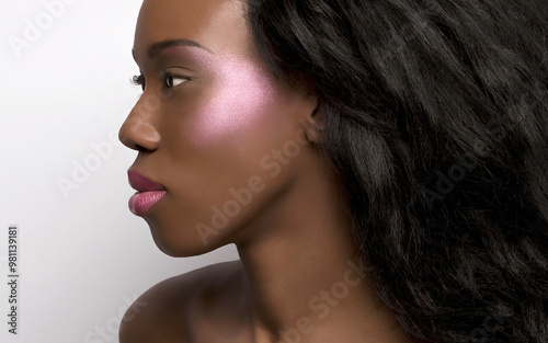 Close-up portrait of a woman with flawless skin and prominent cheekbones against a white background.