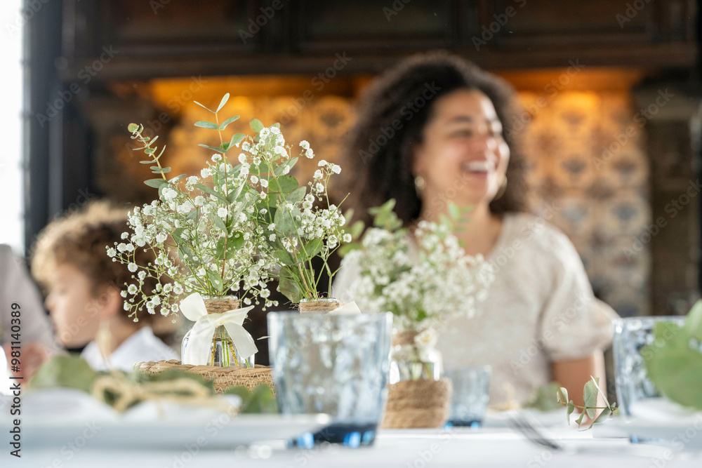 A cheerful woman laughing at a decorated table with white flowers in focus and soft background. A cheerful woman laughing at a decorated table with white flowers in focus and soft background.