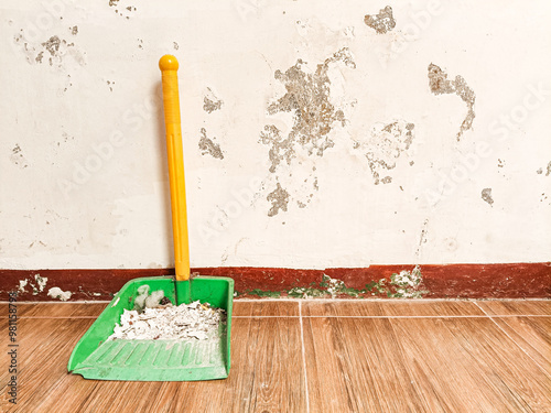 dustpan full of dust against a white pilled wall photo