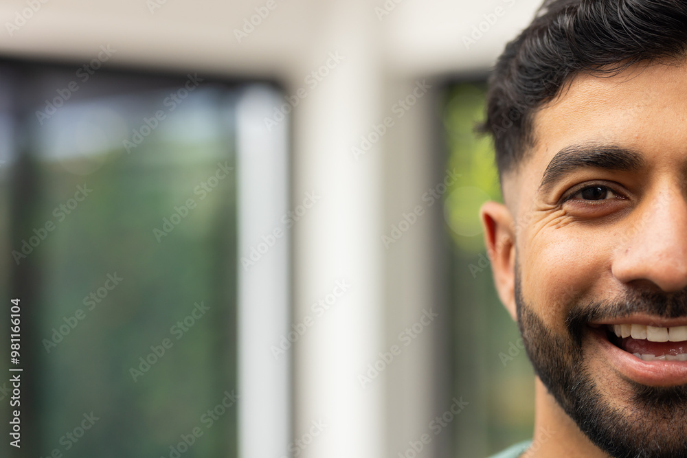 Smiling young Indian man with beard enjoying time indoors, close-up portrait, copy space