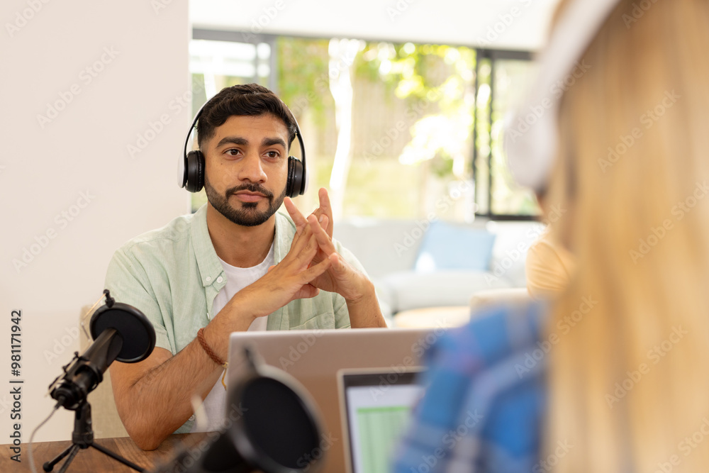 Recording podcast, man wearing headphones sitting at table with microphone Recording podcast, man wearing headphones sitting at table with microphone