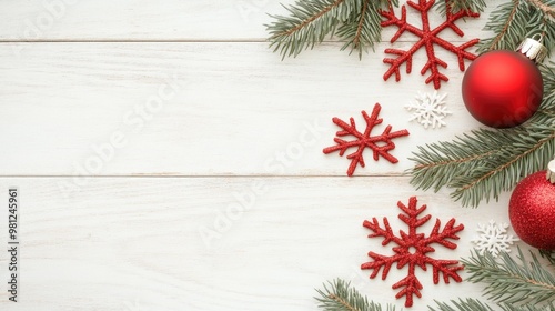 A beautifully decorated wooden tabletop features fir branches, delicate snowflakes, and vibrant red ornaments, creating a warm festive atmosphere for Christmas celebrations