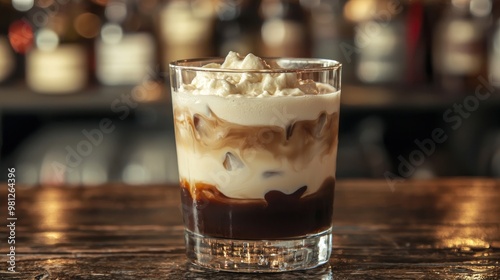 Glass of creamy vodka-based white Russian, with layers of vodka, cream, and coffee liqueur.