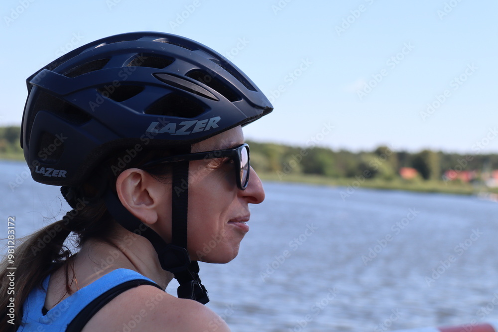 smiling woman in bike helmet and sunglasses looks at river smiling woman in bike helmet and sunglasses looks at river