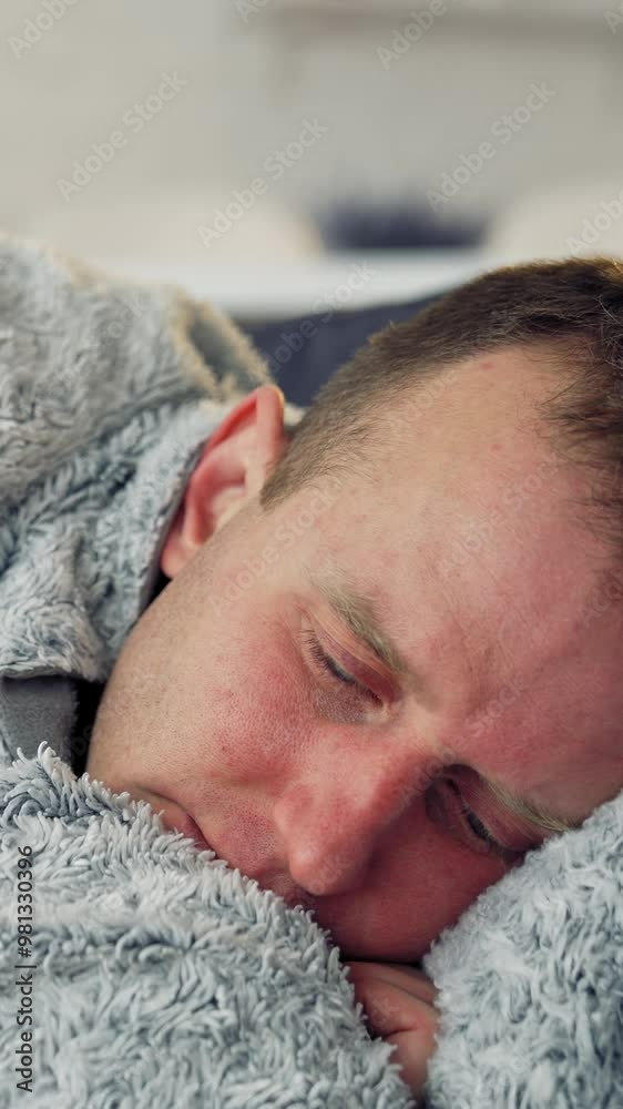 Sick man with a headache during fever. Guy lying in bed covering his head with a warm blanket. Coronavirus pandemic, epidemic. Close-up. Vertical video Sick man with a headache during fever. Guy lying in bed covering his head with a warm blanket. Coronavirus pandemic, epidemic. Close-up. Vertical video