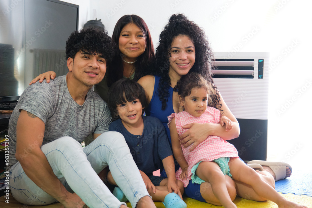 Happy latin family with children posing together on the floor in their living room