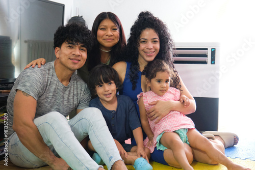 Happy latin family with children posing together on the floor in their living room