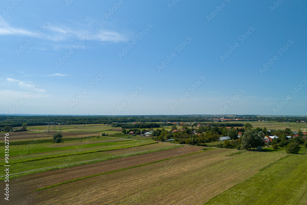 A beautiful aerial view showcasing lush green fields and a serene village under a clear blue sky, perfect for landscape and nature enthusiasts. A beautiful aerial view showcasing lush green fields and a serene village under a clear blue sky, perfect for landscape and nature enthusiasts.