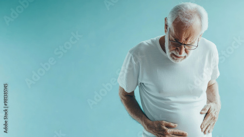 An elderly man holding his stomach in pain on a light background