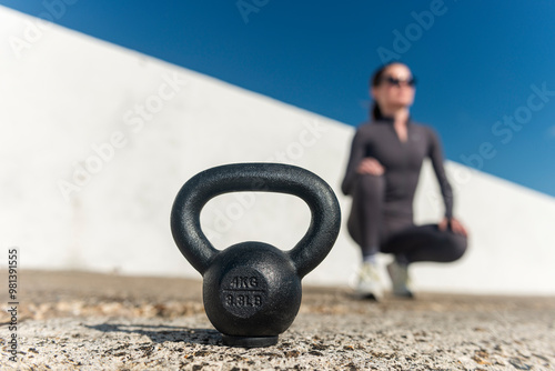 Kettlebell weight with sporty woman outdoors. photo