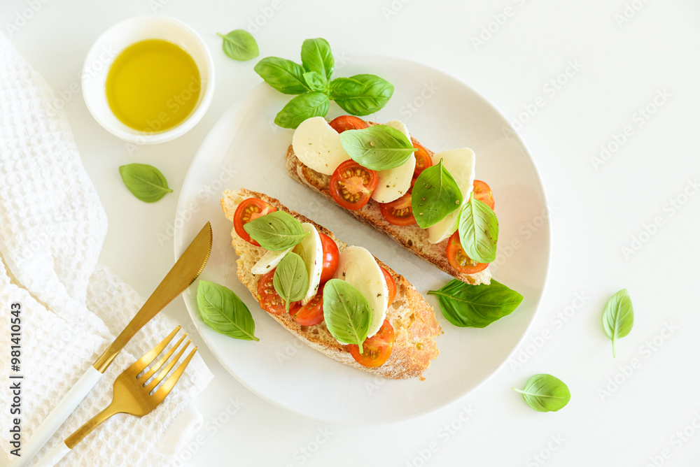 Bruschetta toasts with mozzarella, cherry tomato and basil leaves on white wooden table Bruschetta toasts with mozzarella, cherry tomato and basil leaves on white wooden table