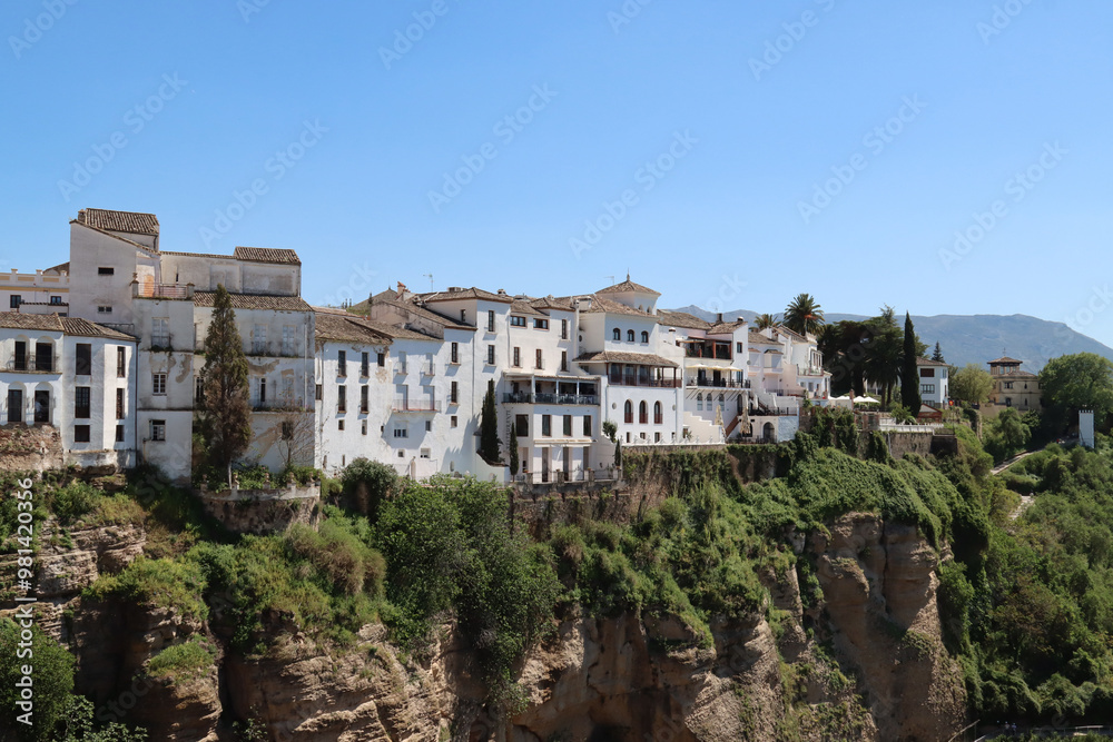 White houses are standing on a cliff overlooking a valley in andalusia White houses are standing on a cliff overlooking a valley in andalusia