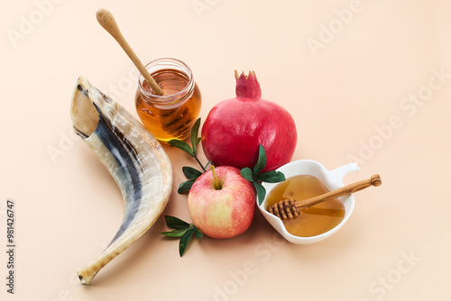 Rosh Hashanah. Rosh Hashanah featuring a shofar, honey, pomegranate, and apple on a beige background. photo