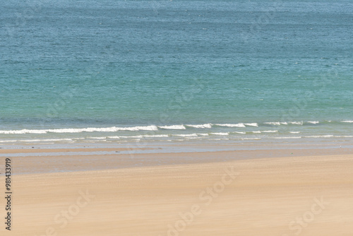 Fine sandy beach in front of a calm and clear turquoise blue sea.