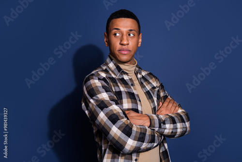 Photo of handsome confident guy wear checkered shirt arms folded looking emtpy space isolated blue color background