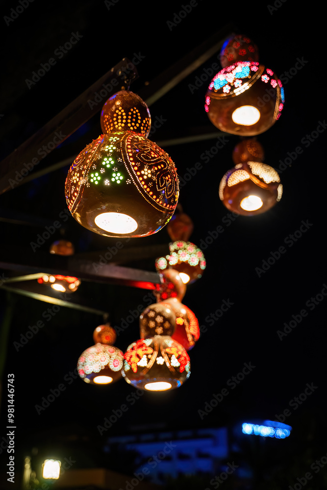 A string of colorful, handcrafted gourd lanterns illuminated at night, creating a beautiful and festive atmosphere.