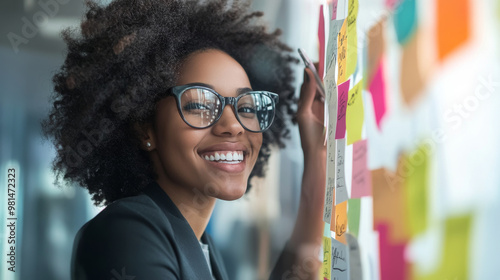 Smiling business owner reviewing goals on a vision board, maintaining a positive outlook while brainstorming ideas photo