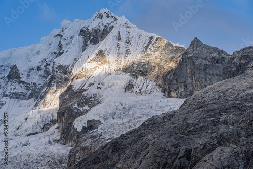 mountain top with glacial and rocky walls. white snow mixed with icy blues and skies with clouds over the crests of the hills, an amazing wallpaper view inviting you to adventure