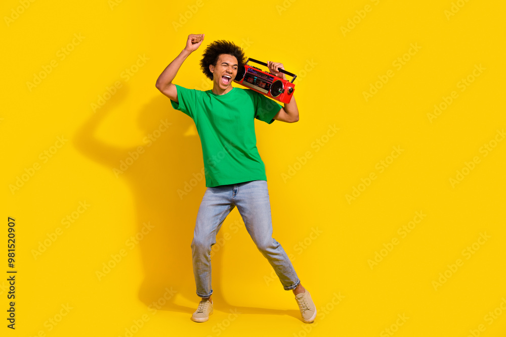 Full length photo of handsome good mood guy wear green t-shirt dancing enjoy boom box songs emtpy space isolated yellow color background Full length photo of handsome good mood guy wear green t-shirt dancing enjoy boom box songs emtpy space isolated yellow color background