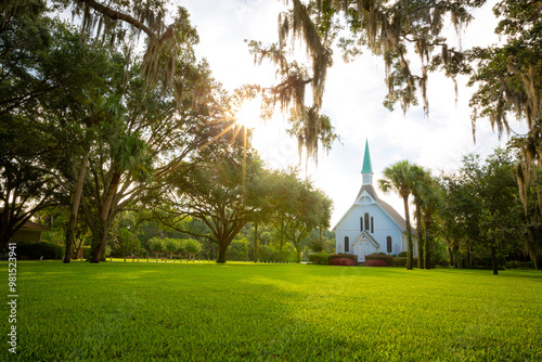 Bild auf Leinwand White episcopal church with grassy yard surrounded by trees