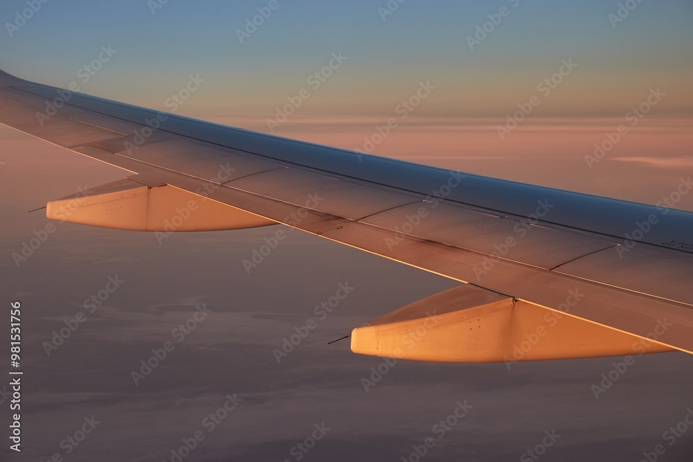 Obraz premium Flying on a plane, rising sun hitting wing