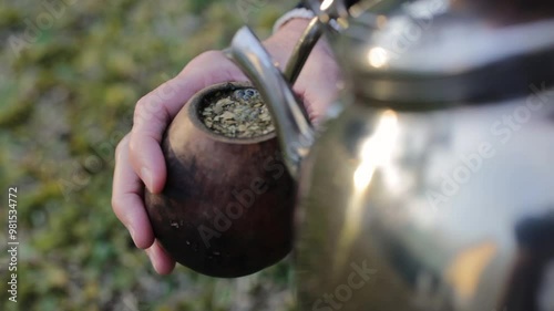 An adult woman preparing yerba mate tea with hot water, a traditional South American infusion. It is a typical social drink from Argentina, Uruguay, Brazil, and Paraguay	
 photo