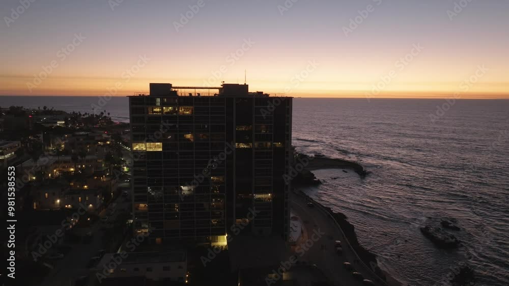 Aerial view of high rise building in La Jolla California overlooking the Children's Pool and Pacific Ocean just after the sunset with twilight views as lights begin to turn on around the city Aerial view of high rise building in La Jolla California overlooking the Children's Pool and Pacific Ocean just after the sunset with twilight views as lights begin to turn on around the city