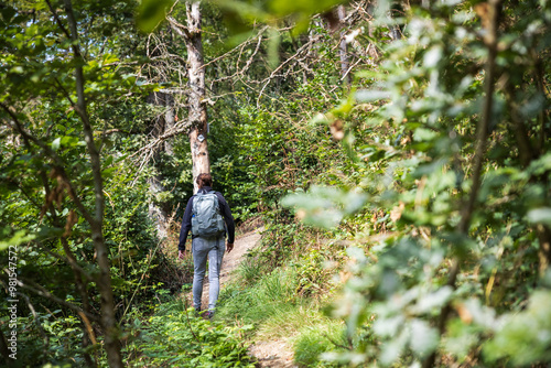 Frau mit Rucksack wandert alleine durch den Wald photo