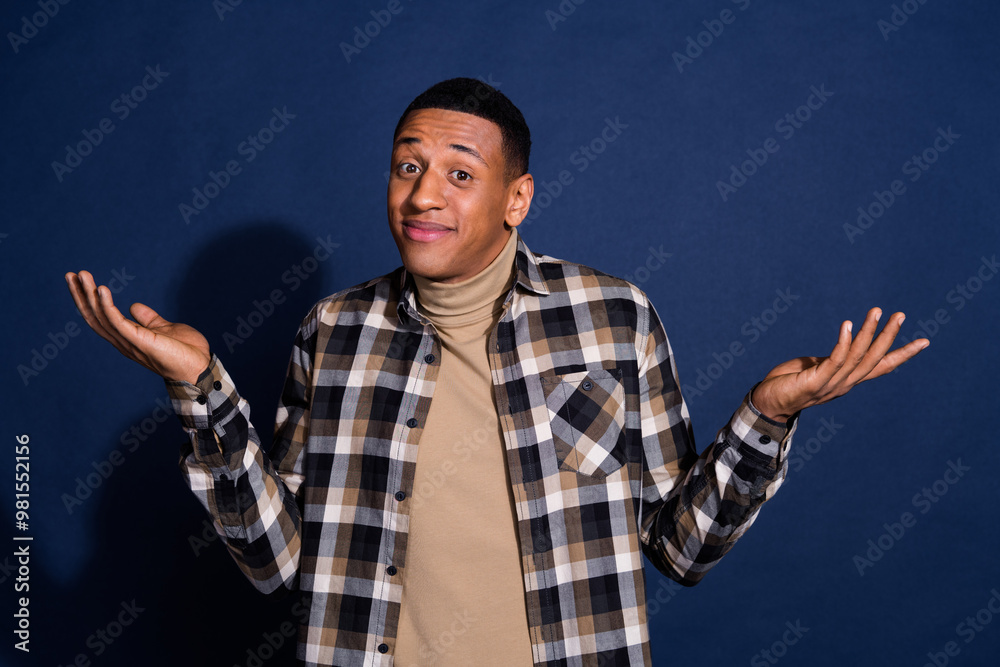 Photo portrait of handsome young man shrug shoulders dressed stylish plaid garment isolated on dark blue color background Photo portrait of handsome young man shrug shoulders dressed stylish plaid garment isolated on dark blue color background