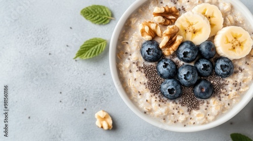 A close-up of a nutritious oatmeal bowl topped with fresh blueberries, banana slices, walnuts, and chia seeds arranged aesthetically, representing a healthy breakfast option. photo