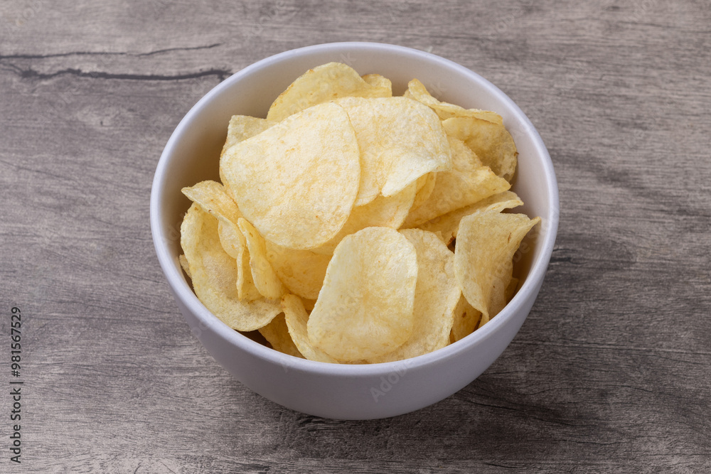 Potato chips in a bowl over wooden table Potato chips in a bowl over wooden table