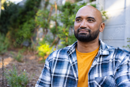 Smiling man in plaid shirt enjoying outdoor time in home garden photo